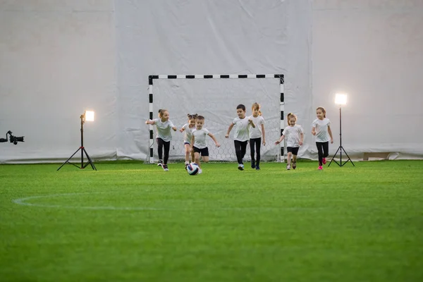 Kleine Kinder spielen Fußball und rennen über den Platz — Stockfoto