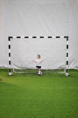 Sahada futbol gol ortasında duran küçük bir kız