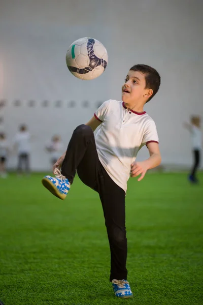 A little boy throwing ball on the field playing football with other kids