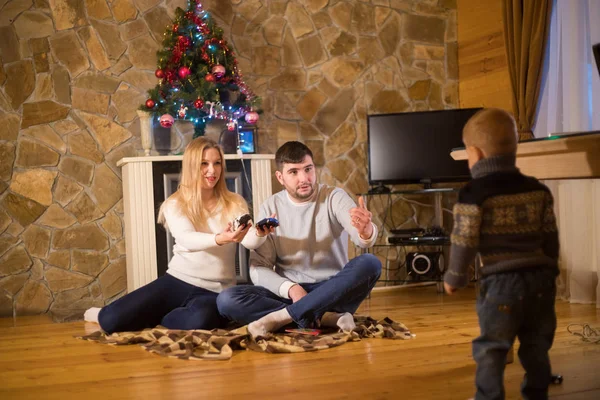 Familia joven sentada en una casa acogedora. Padres llamando a su hijo pequeño — Foto de Stock