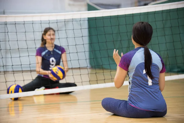 障害者のスポーツ.2 つの若い女性の床に座って、バレーボールします。ポニーテールの女性. — ストック写真