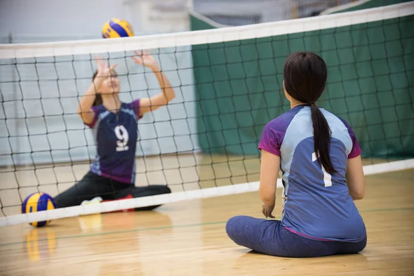 障害者のスポーツ.トレーニング。床に座って、バレーボールを再生する 2 つの若い女性. — ストック写真