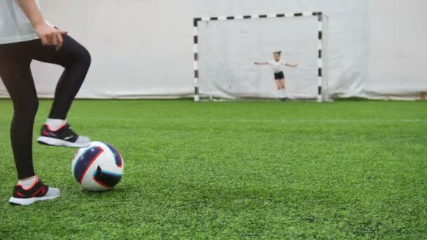 Niños jugando al fútbol en el estadio de fútbol interior. Un niño pequeño se prepara para golpear la portería — Vídeos de Stock