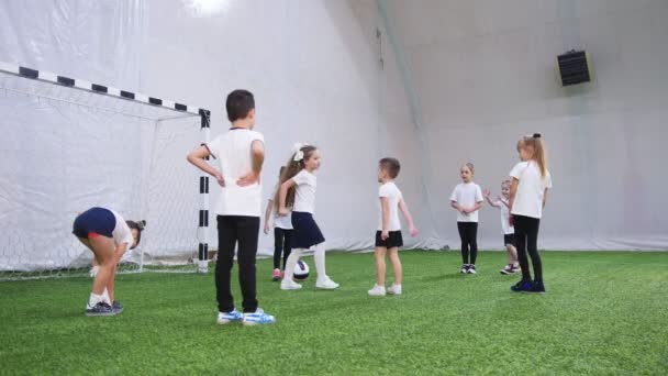 Crianças jogando futebol na arena de futebol indoor. Discutindo sobre a tática — Vídeo de Stock