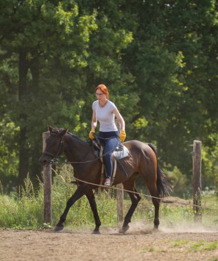 Beyaz tişört ve gözlük bir binicilik doğada bir kızıl saçlı kadın.