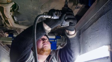 Araba Servisi. Kalın zencefil mekanik adam muayene çukura duran ve bir araç ile çalışma