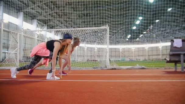 Dos jóvenes atléticas comienzan a correr en el campo deportivo — Vídeos de Stock