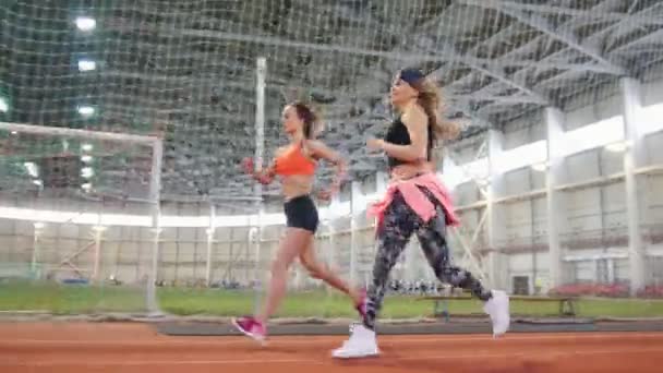 Duas jovens atléticas correndo na arena esportiva dentro de casa — Vídeo de Stock