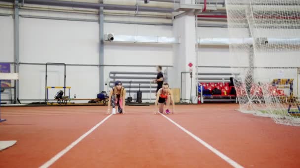 Két fiatal sportos nők kezdenek sport arénában a futópálya. Képzés — Stock videók