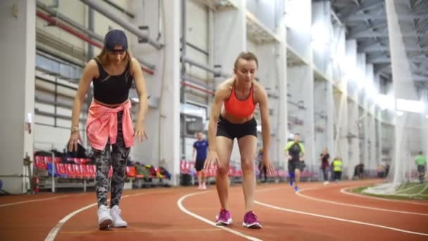 Két fiatal sportos nők arra készül, hogy futtassa a futópálya. Az emeleten csökkenő — Stock videók