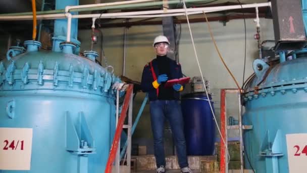 Een ingenieur van de man loopt naar een apparatuur en het maken van notities over de fabriek — Stockvideo