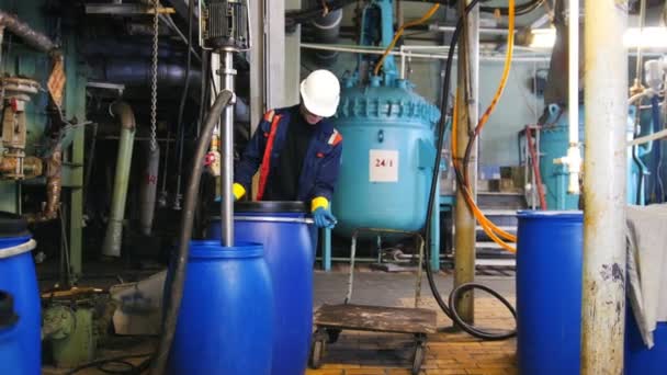 Un homme ingénieur dans la fabrication met un baril sur un chariot et le roule 