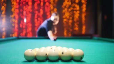 Bilardo kulüp. Bir adam hedefleyen ve topa vuruyor. Neredeyse yerde kaldı topları