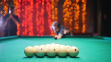 Bilardo kulüp. Bir adam hedefleyen ve topa vuruyor. Oyun başlar