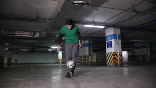 Молодой человек, выполняющий профессиональные футбольные трюки на подземной парковке — стоковое видео