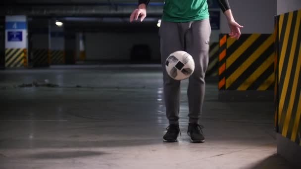 Молодой человек тренирует свои футбольные навыки на подземной парковке — стоковое видео