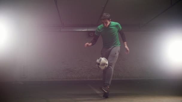 Parking souterrain. Un jeune footballeur entrainant des tours de football. Équilibrer la balle sur le pied — Video