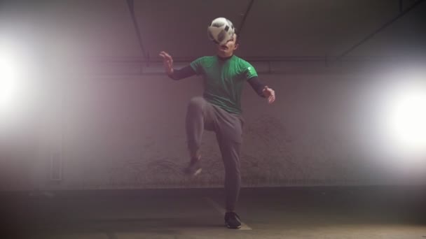 Подземная парковка. Молодой футболист тренирует футбольные трюки. Бросай мяч на голову и балансируй. — стоковое видео