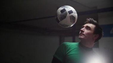 Yer altı otoparkı. Bir genç futbol adam eğitim futbol hileler. Bir omuz ile topa vuruyor