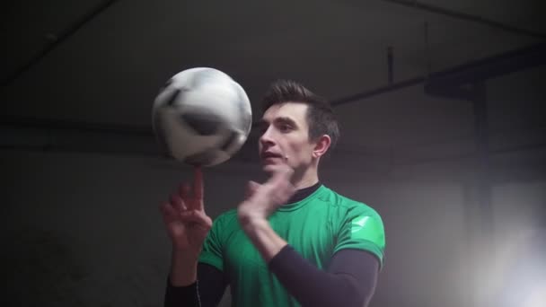 Tiefgarage. ein junger Fußballmann, der Fußballtricks trainiert. Drehen des Balles am Finger — Stockvideo