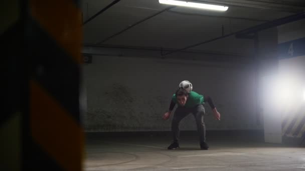 Parking souterrain. Un footballeur athlétique qui s'entraîne. Frapper le ballon, l'équilibrer et se rapprocher de la caméra — Video