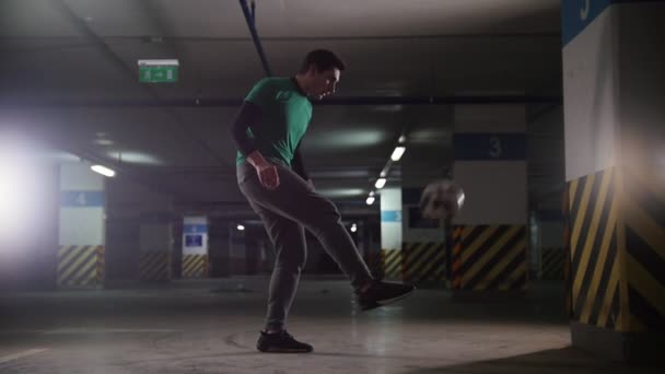 Estacionamento subterrâneo. Homem de futebol atlético treinando suas habilidades de futebol. Chutando para trás a bola da parede — Vídeo de Stock