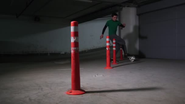 Parking souterrain. Un footballeur athlétique qui s'entraîne. Mener la balle contournant les obstacles — Video