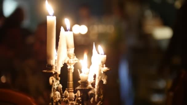 Kerzen flammen im Restaurant, jemand bewegt sich auf dem schwarzen Hintergrund hinter den Kerzen — Stockvideo
