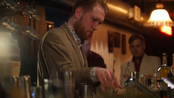 Jonge barman zet ijs in een glas met cream likeur en geeft de afgewerkte drank — Stockvideo