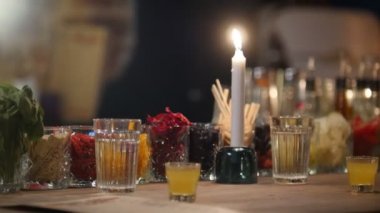 Gözlük ve bir mum renkli kokteyl ingridients stand bir bar counter