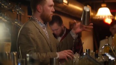 Dökme ve yumuşak iç aydınlatma barda bir içki sallayarak genç profesyonel barmen