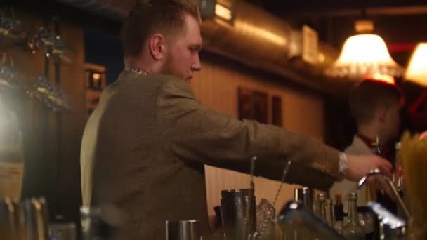 Jeune barman professionnel versant et mélangeant liqueur rouge et crème — Video