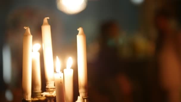 Ein paar Kerzen flammen auf, jemand bewegt sich auf dem schwarzen Hintergrund hinter den Kerzen — Stockvideo