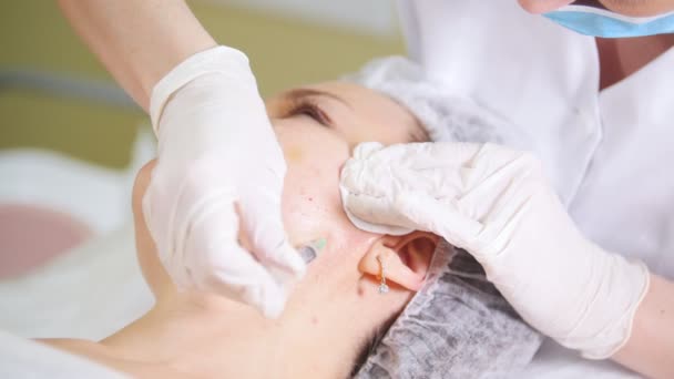Косметолог проводит косметическую процедуру мезотерапии лица, делая инъекции в щеку под клиентов в косметологической клинике . — стоковое видео