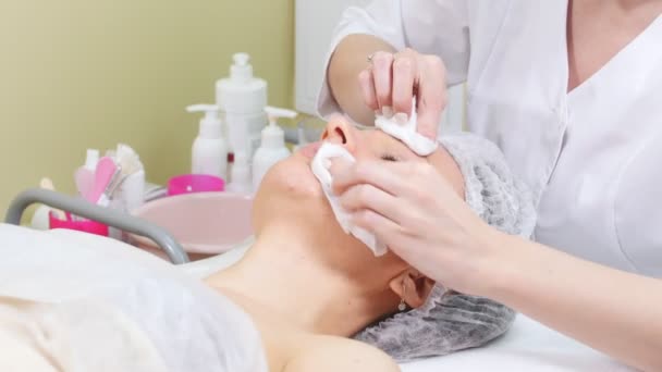 Cosmetologist esfregando o creme nas bochechas dos clientes fazendo procedimentos cosméticos limpeza do rosto na clínica de cosmetologia . — Vídeo de Stock