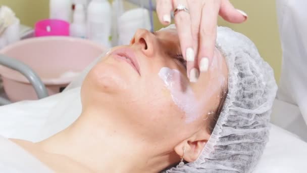 Косметолог наносить крем на щоки клієнтів, роблячи процедури очищення обличчя в косметологічній клініці . — стокове відео
