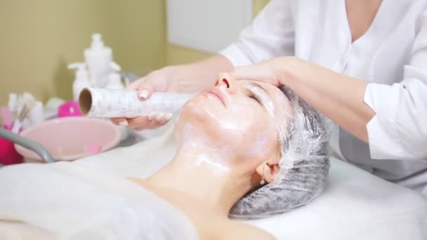 Cosmetologist wraping στην ταινία πελάτες πρόσωπο κάνει αισθητικές επεμβάσεις καθαρισμό του προσώπου στην κοσμετολογία κλινική. — Αρχείο Βίντεο