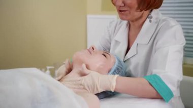 Masaj tedavisi kozmetik kliniğinde. Doktor krem istemci yüzündeki dağıtır