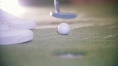 Mini golf oynuyor. Deliğe topu ve isabet bir kişi alır