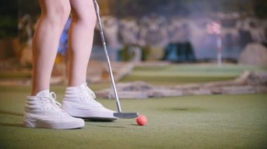 Mini golf oynamak genç bir kadın. Hemen bacaklarını açıp çerçeve