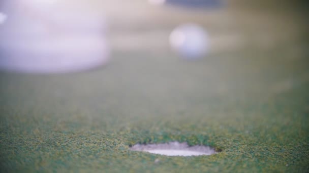 Mini golf. A person hitting the ball and it gets in the hole — Stock Video