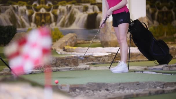 Eine junge Frau beim Minigolfen. Zielflagge auf dem blauen Vordergrund — Stockvideo