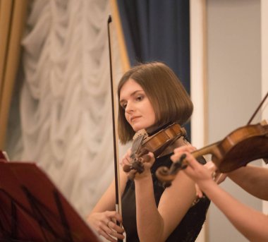 Güzel genç kadın konser salonunda keman çalıyor