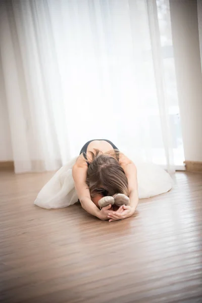 Tancerka robi, rozciąganie siedząc na podłodze w studio — Zdjęcie stockowe