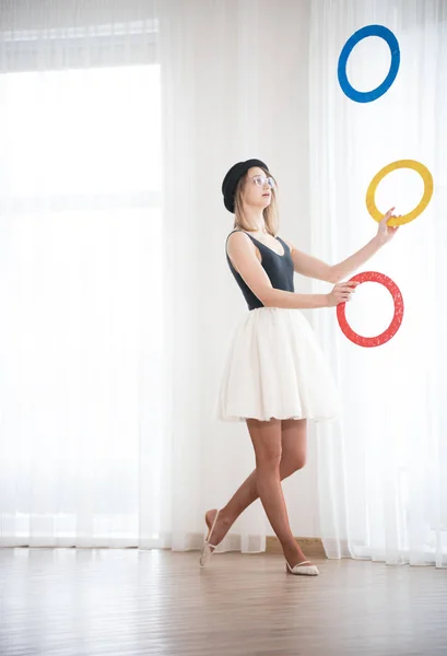 Mujer joven en un sombrero hace malabares con anillos en el estudio — Foto de Stock