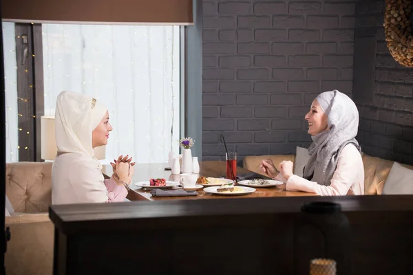 Twee jonge Moslimvrouwen chatten aan een tafel in een café — Stockfoto