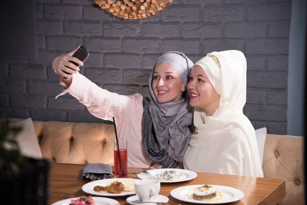 Twee moslim meisje een selfie nemen aan een tafel in een café — Stockfoto