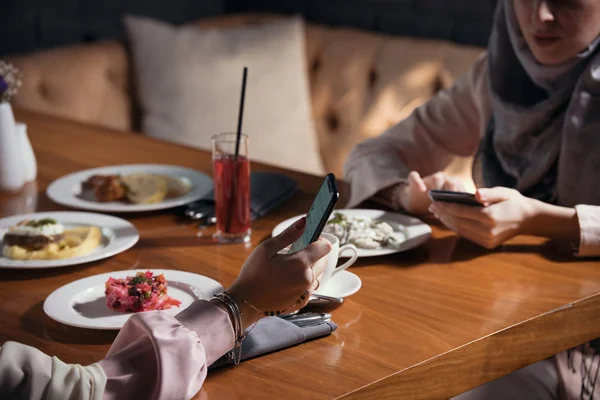 Två muslimska kvinnor sitta med prylar vid ett bord i en restaurang — Stockfoto