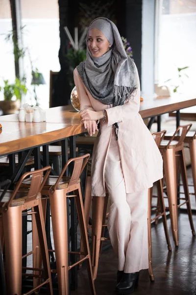 Een jonge moslimvrouw zittend op een stoel in een restaurant — Stockfoto