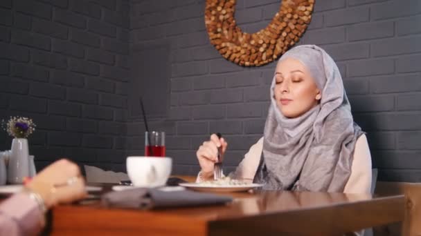 Dos musulmanas sentadas en una mesa en un restaurante. Un camarero trae el pedido — Vídeos de Stock